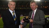 O presidente da Federação Escocesa de Futebol, Campbell Ogilvie, entrega a Kenny Dalglish o troféu da UEFA por ter somado 100 internacionalizações