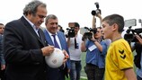 Observado por um jovem jogador e pelo presidente da Federação de Futebol da Arménia (FFA) Ruben Hayrapetyan (centro), o Presidente da UEFA, Michel Platini, assina uma bola de futebol no centro de treino das selecões locais