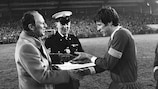 Lverpool's Emlyn Hughes receives his winners' medal from UEFA General Secretary Hans Bangerter after the 1977 Super Cup success against Hamburg